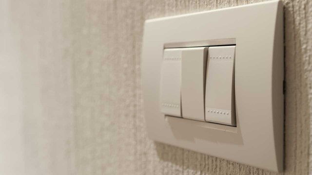 Different types of light switches with varying buttons push attached to a concrete wall of a house