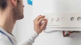 man adjusting the knob on a boiler control panel looking for ways to lower electric bill in winter